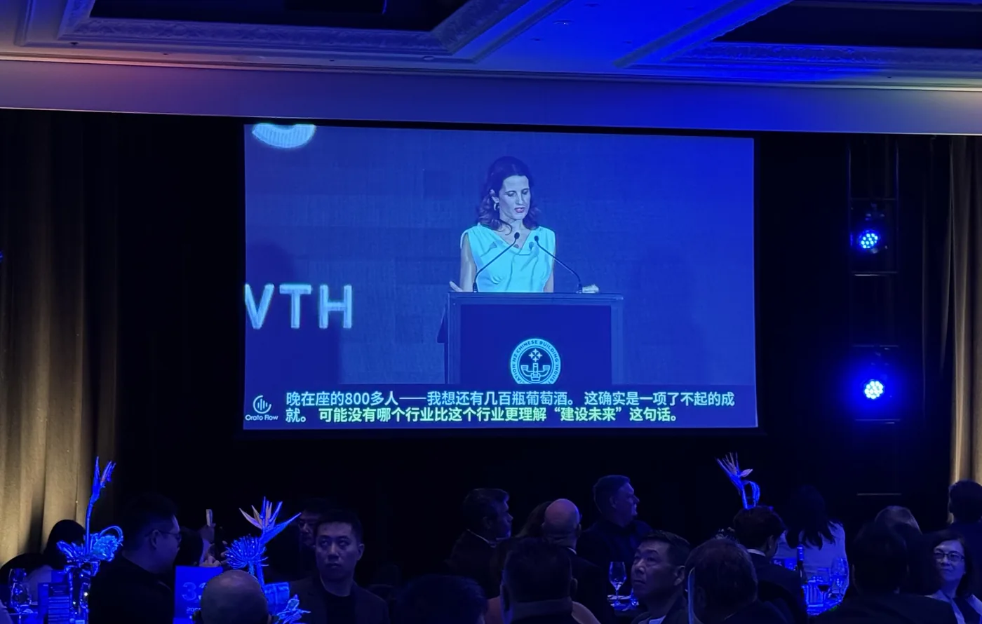 Nicola Willis, Minister of Finance, speaking at the NZCBIA lectern on the main screen, with Orato Flow’s live Chinese captions running beneath.