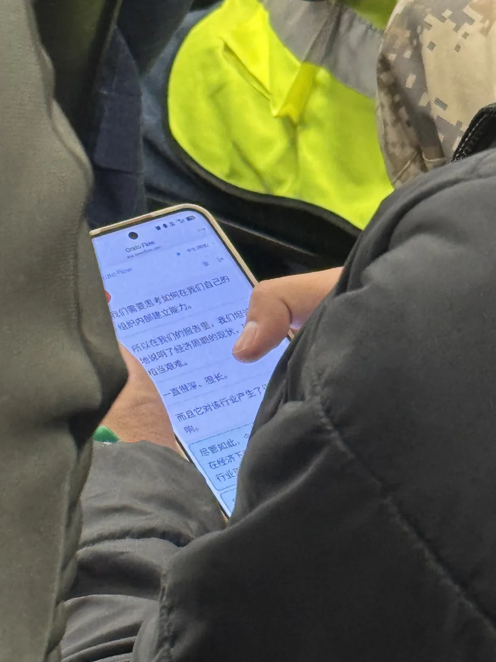 An attendee in a hi-vis vest reading Orato Flow’s live Chinese translation on a phone during the report launch.